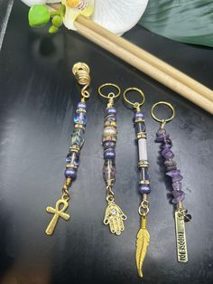 four different types of beads and charms on a black surface next to a bamboo stick