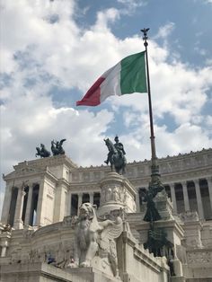 the italian flag is flying in front of an ornate building with statues on it's sides