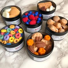 four containers filled with different types of candy and candies on a marble counter top