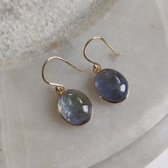 ITEM DESCRIPTION: >> The earrings are made from Solid 14K Yellow Gold. Gemstone used is absolutely natural and ethically sourced. >> Naturally occurring Bi-color Tanzanite Cabochon with shades of blue and green in bezel setting is studded on it with utmost precision. >> This is a minimalist design and is absolutely hassle-free and everyday jewelry. Gem: Bi-color Tanzanite Gem size: 10x12 mm Gem weight: 12.22 carats Gold purity: 14K (58.33% approx.) Gold weight: 0.70 grams Gross weight: 3.14 gram Handmade Jewelry Box, Tanzanite Jewelry, Bezel Earrings, Tanzanite Earrings, 22 Carat Gold, Yellow Gold Earrings, Yellow Gold Earring, Unique Gemstones, December Birthstone