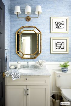 a bathroom with blue wallpaper and gold mirror