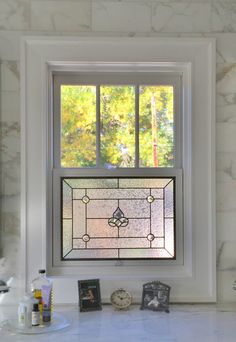 a bathroom window with a stained glass design on it's side and the sink below