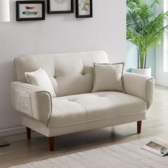 a living room with white furniture and pictures on the wall