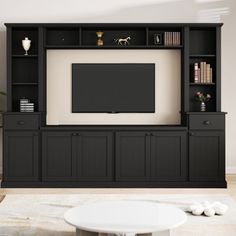 a living room with black entertainment center and white coffee table in front of the tv