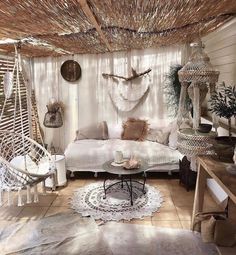 the room is decorated in white and has hammock hanging from the rafters