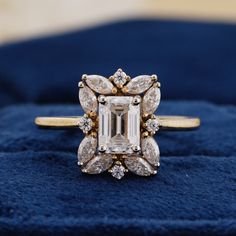 an emerald and diamond ring sitting on top of a blue velvet