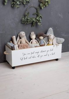 a wooden box filled with stuffed animals sitting on top of a table next to a wreath