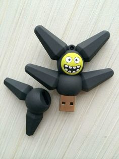 a black and yellow toy is attached to a usb stick with an angry face on it