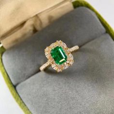 an emerald and diamond ring in a box