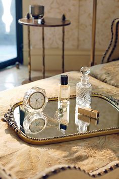 a mirrored tray with various items on it sitting on a table next to a mirror