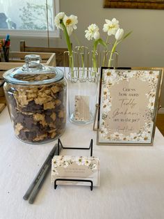 a table topped with cookies and flowers next to a glass jar filled with chocolate chips