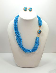 Vintage Turquoise Blue  Lucite Multi Strand Pressed Molded Bead Ornate Box Clasp Necklace And Earrings Set A simple, lightweight 8 strands of molded plastic faceted  translucent and opaque beads capped off with gold tone caps and a round gold tone box clasp that features matching beads. The Matching clip on earrings are done in the same style as the clasp. The beads in the earrings have some discolouration due to age/glue. Length: 23 inches Earrings measure:21 mm This is a vintage item, it has b Handmade Light Blue Multi-strand Jewelry, Light Blue Multi-strand Jewelry Gift, Light Blue Multi-strand Jewelry For Gift, Light Blue Multi-strand Jewelry As Gift, Traditional Blue Faceted Beads, Festive Blue Jewelry With Polished Beads, Traditional Blue Beaded Necklaces For Party, Blue Polished Beaded Necklaces For Festive Occasions, Clasp Necklace