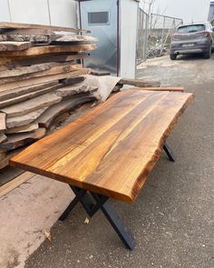 a wooden table sitting on top of a metal stand next to a pile of wood