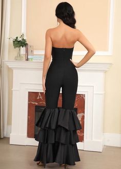 the back of a woman in a black jumpsuit with ruffles on it