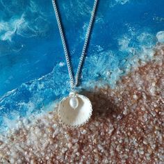 Embrace the beauty of the ocean with our handcrafted Seaside Elegance necklace, a stunning piece that captures the essence of the shore. This necklace features a natural seashell pendant, carefully selected for its unique shape and intricate patterns, paired with a lustrous freshwater pearl that adds a touch of elegance. Each necklace is lovingly handcrafted, ensuring that no two pieces are exactly alike--just like the treasures you find on the beach. The combination of organic elements and timeless pearls creates a perfect harmony, making this necklace a versatile accessory that can complement any outfit, whether you're dressing up for a special occasion or adding a touch of coastal charm to your everyday look. Features: Natural Seashell: Handpicked for its distinctive beauty, bringing th Ocean-inspired Abalone Shell Gift, Ocean-inspired Shell-shaped Mother Of Pearl Jewelry, Ocean-inspired Pearl Charm Jewelry For Gifts, Ocean-inspired Pearl Charm Jewelry As Gift, Ocean-inspired Pearl Charm Jewelry Gift, Ocean-inspired Pearl Pendant Jewelry, Ocean-inspired Shell-shaped Pearl Pendant Jewelry, Shell-shaped Jewelry With Pearl Pendant, Shell-shaped Pearl Pendant Jewelry