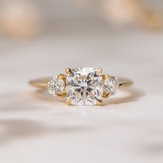 three stone diamond ring on white surface with blurry light in the backround