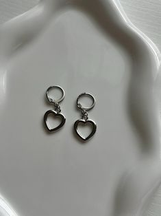 A simplistic earrings pair made with silver heart charms. Subtle enough to wear for the rainiest days, and elegant enough to dress up. Includes 1 pair of earrings (2 hoops). Silver Nickel-free Hoop Earrings For Valentine's Day, Trendy Everyday Heart Dangle Earrings, Minimalist Dangle Heart Earrings, Trendy Dangle Heart Earrings, Trendy Pierced Heart Dangle Earrings, Silver Minimalist Heart Charm Earrings, Minimalist Hoop Earrings With Heart Charm, Silver Minimalist Heart Earrings With Charm, Minimalist Dangle Earrings For Valentine's Day