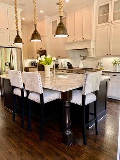 a large kitchen island with four chairs and lights hanging from it's ceiling above