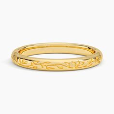 a yellow gold wedding band with leaves on the outside and an engraved design in the middle