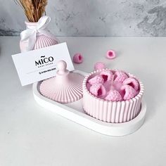 two pink soaps sitting on top of a white tray next to a vase filled with flowers