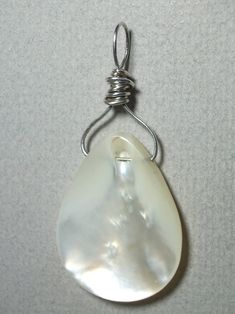 Mother of Pearl Bead Pendant Wire Wrapped in .925 Sterling Silver Round Wire This refreshing and enlightening mother of pearl bead displays a fine fluid silver-white to iridescent (pearlescent) sheen. Versatile, it wears well with almost any color of clothing, including both gray and brown based color tones. It gives a sharp contrast to darker colors and a pleasant blend to lighter/pastel colors. It is also a nice match with most earth tone colors. Consistent color and teardrop shape give some a White Shell-shaped Jewelry With Pearl Pendant, White Shell-shaped Pearl Drop Necklace, White Teardrop Mother Of Pearl Jewelry, Elegant Iridescent Drop Jewelry, Pearl White Shell Jewelry With Pearl Drop, White Wire Wrapped Drop Jewelry, Mother Of Pearl Drop Jewelry For Gift, Drop-shaped Mother Of Pearl Jewelry For Gifts, Pearl White Mother Of Pearl Shell Jewelry