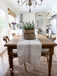 a wooden table topped with a basket filled with flowers next to a light fixture above it