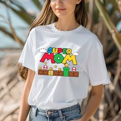 a woman wearing a white t - shirt with the words super mom printed on it