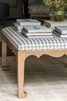 a coffee table with books on it and a vase full of flowers in the background