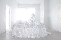 an empty room with white sheets on the floor