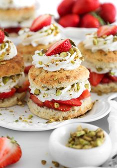 strawberry shortcakes with whipped cream and pistachio toppings on white plates