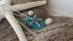 a starfish and sea glass necklace sitting on a beach chair next to a seashell