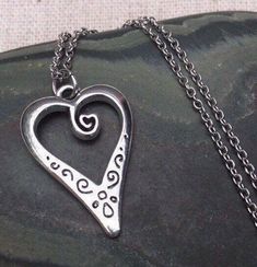 This is such a unique and whimsical heart pendant necklace.  It has incredible detail and another little heart showcased inside the main heart.  This would make a very sweet and meaningful gifts for a loved one on any occasion.  The heart measures 1” long by 5/8” wide and is made from allergy free plated silver.  It hangs from a simple 18” stainless steel necklace chain.I have matching earrings in my shop, if you would like the whole set.  Here is the link........... https://etsy.me/30EwF2x Than Bohemian Heart Pendant Charm Necklace Gift, Metal Heart Necklace With Open Heart Charm, Bohemian Silver Heart Charm Necklaces, Metal Heart Pendant Necklace, Bohemian Silver Heart Charm Necklace, Metal Heart Necklace With Heart Beads, Metal Heart Pendant Necklace For Valentine's Day, Metal Heart Pendant Necklace As Gift, Metal Heart Necklace With Open Heart And Heart Beads