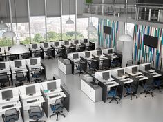 an office filled with desks and computers in front of large windows overlooking the city