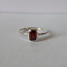 Introducing our exquisite Mini Garnet Silver Ring, a true embodiment of elegance and sophistication. This mesmerizing piece features a captivating red stone, delicately perched atop a pristine white sheet, creating a striking contrast that is sure to catch the eye. Crafted with meticulous attention to detail, this Garnet Rectangle Ring showcases a sleek and timeless design, making it an ideal choice for any occasion. Whether it's a promise ring or a midi silver ring, this Silver Baguette Ring is Gold Unique Jewelry, Silver Red Ring, Garnet Silver Ring, Minimalist Birthstone Ring With Baguette Cut Gemstone, Minimalist Birthstone Ring With Baguette Cut, Minimalist Baguette Cut Birthstone Ring, Minimalist Emerald Cut Crystal Gemstone Ring, Minimalist Emerald Cut Sterling Silver Birthstone Ring, Elegant Sterling Silver Stackable Ruby Ring