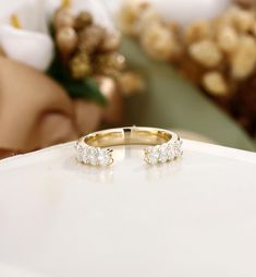 two diamond wedding rings sitting on top of a white table with flowers in the background