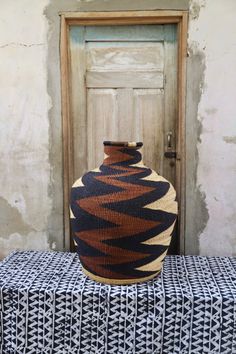 a brown and black vase sitting on top of a table