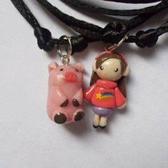 two necklaces that have animals on them and one has a girl holding a pig