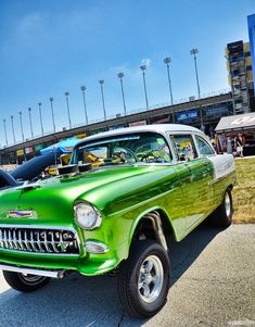 an old green car is parked in the parking lot