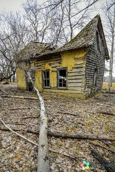 an old run down house in the middle of a field with fallen leaves on the ground