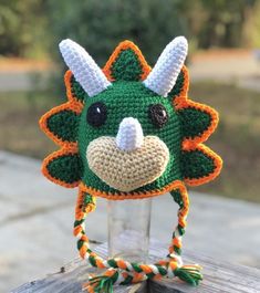 a crocheted green and orange hat with horns on the head is sitting on a wooden table