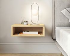 a wooden shelf with a mirror above it on the wall next to a white bed