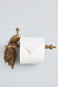 a toilet paper holder with a gold peacock on it's side and a white envelope in the middle