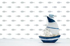 a white and blue sailboat with fish on it in front of a wallpapered background