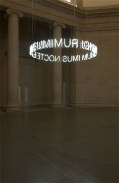 an empty room with columns and a neon sign on the wall that reads museum mus nocte