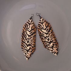 two pairs of beaded earrings sitting on top of a white and gray plate,