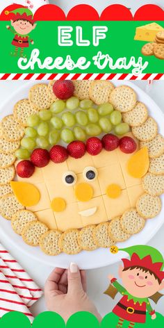 an elf cheese tray with grapes, strawberries and crackers on it for christmas