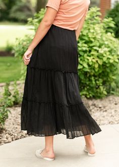 The Serena Gauze Maxi Skirt is an elevated and modest basic you will love! This high-quality maxi length skirt features an eyelet lace skirt that is tiered and adorned with small ruffles. It is lined and crafted from 100% cotton fabric, and is fully lined. The skirt is sure to be an enduring piece in any wardrobe! Style | Maxi Color | Black SIZING TIPS Fit | Semi-Fitted Stretch | Mid-Stretch Model | True to Size Elegant Tiered Bottoms With Elastic Waistband, Tiered Gathered Skirt In Solid Color, Relaxed Tiered Maxi Skirt, Relaxed Tiered Maxi Skirt With Layered Hem, Solid Color Tiered Gathered Skirt, Modest Tiered Skirt, Solid Color Ruffled Maxi Skirt, Modest Relaxed Tiered Skirt, Flowy Maxi Skirt With Ruffle Hem