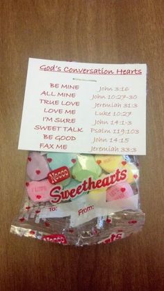 candy wrapped in cellophane with conversation hearts attached to the wrapper, on top of a wooden table