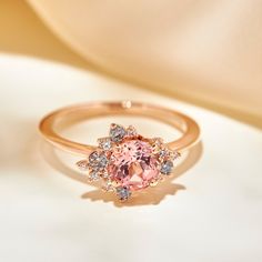 100% recycled precious metal Set in the center with a lovely approx. 1.25ct (6mm) round cut lab grown rosé sapphire. With a blush hue reminiscent of the color of morganite, our rosé sapphire features a slightly more saturated pink, and it offers a much better durability than morganite, making it ideal for an engagement ring! Available in two different tones: a hint of peach, or a hint of lilac One of a kind asymmetrical cluster halo featuring sparkly colorless lab grown diamonds, peppered with m Pink Diamond Gold Engagement Ring, Pink Sapphire Engagement Ring Rose Gold, Engagement Rings Pink, Rose Gold Morganite Engagement Ring, Pink Moissanite Ring, Pink Stone Engagement Rings, Pink Sapphire Engagement Ring, Montana Sapphire Engagement, Montana Sapphire Engagement Ring