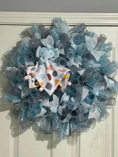 a blue and white mesh wreath with a teddy bear on it's front door